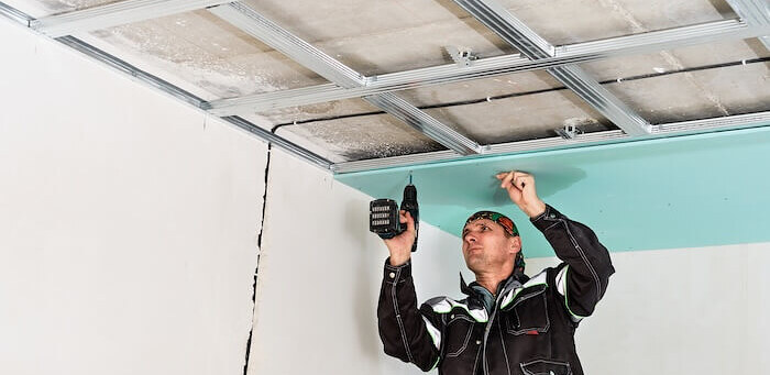 Installer fixing a suspended ceiling grid to the soffit