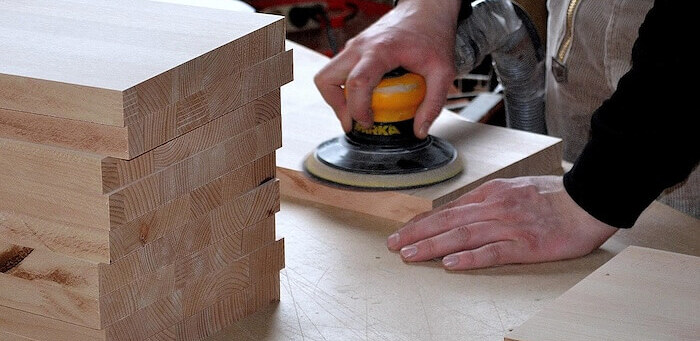 Carpenter sanding a timber panel in the joinery workshop