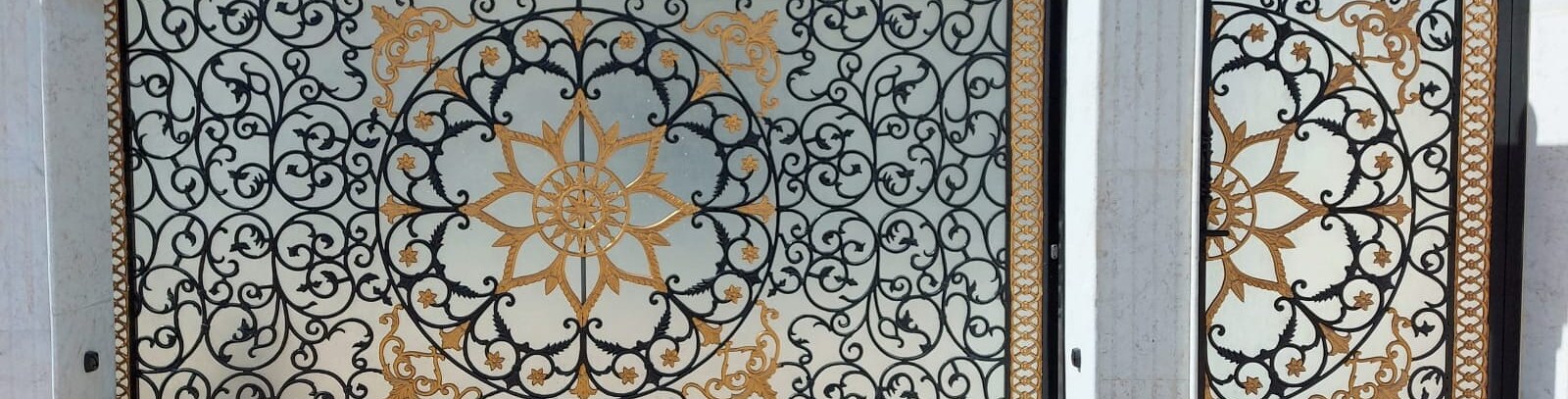 Ornate wrought iron gates with gold leaf detailing at a villa entrance